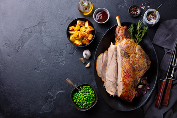 Roasted lamb leg with potato and green peas. Black background. Copy space. Top view. - 352292503