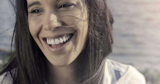 Beautiful woman laughing and smiling on a sunny day by the river woth perfect white teeth
