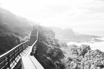 Obraz premium wooden path next to sea on rocks