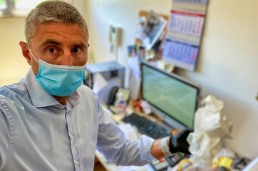 Fototapeta na wymiar Working office in covid-19 outbreak. Man with mask and gloves cleaning room