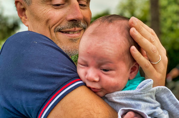 Fototapeta premium Man holding his newborn baby outdoor