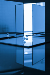 Creative composition of a labyrinth composed of square-shaped mirrors, two glass marbles represent two abstract men heading towards the exit.