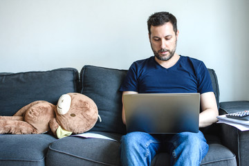 Caucasian man sitting in sofa and using laptop. Concept of Home office