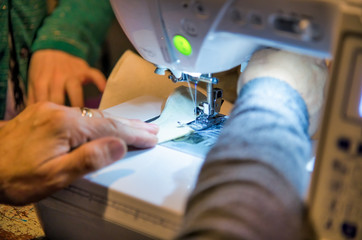 Woman using sewing machine, detail on the hands