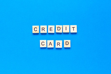 wooden letters credit card on a blue background. banner, free metos, space for text, top view, flat layout