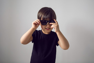boy in a black t-shirt stands at home against the background of a white room