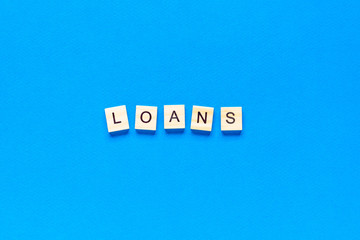 Obraz premium loans inscription in wooden letters on a blue background, flat layout, top view, banner