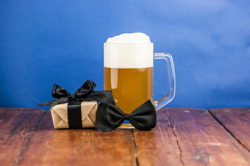 mug of beer with gift box on wooden table. beer party. holiday with friends