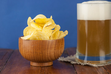 Beer glass with beer and smoked fish close-up. Beer mug with beer and potato chips, crackers on a wood background and copy space.