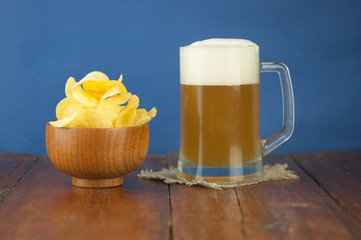 Beer glass with beer and smoked fish close-up. Beer mug with beer and potato chips, crackers on a wood background and copy space.