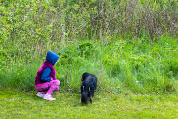 kid with small black do against green jusy grass