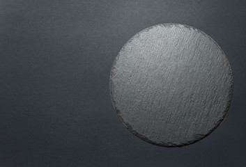 Round black slate dish plate top view empty copy space.