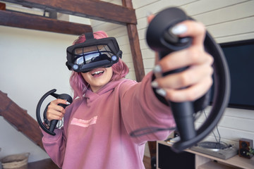 Excited teen hipster girl playing virtual reality video game wear vr goggles headset hold...