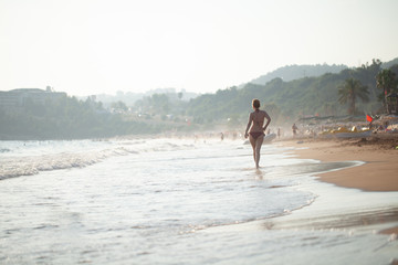 beautiful girl in a swimsuit walks along the beach, the concept of a healthy lifestyle and rest in silence