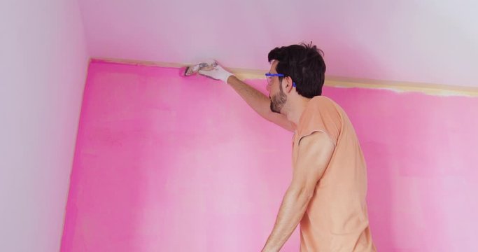 Pittore sta pitturando la parete di una stanza di rosa
