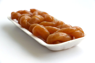 Traditional South African sweet koeksisters covered in syrup, isolated in a polystyrene tray on white background