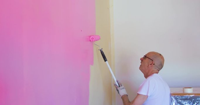 Pittore sta pitturando la parete di una stanza di rosa