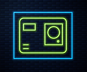 Glowing neon line Action extreme camera icon isolated on brick wall background. Video camera equipment for filming extreme sports. Vector