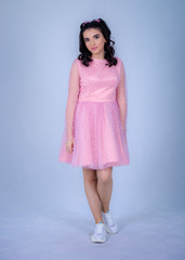 Portrait Of Beautiful Young girle Standing Against blue Background,girl in a pink dress,Happy cheery smiling young cute girl posing isolated,White running shoes