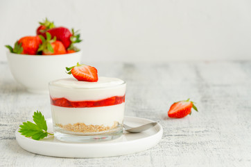 No baked strawberry cheesecake in a glass on a wooden background. Summer cold dessert. Horizontal, copy space.