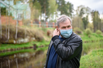 Happy man on a nature walk by the river. The man removes the medical mask from his face.