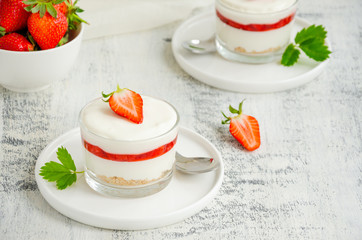 No baked strawberry cheesecake in a glass on a wooden background. Summer cold dessert. Horizontal, copy space.