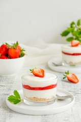 No baked strawberry cheesecake in a glass on a wooden background. Summer cold dessert. Vertical, copy space.