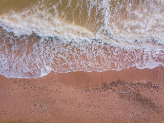Fototapeta na wymiar Top down view of waves breaking in the sand, flying over tropical sandy beach and waves