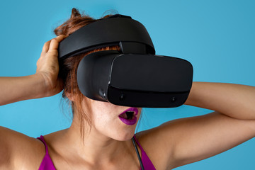 Young woman wearing virtual reality glasses with surprised expression