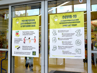 KALININGRAD, RUSSIA. Information sanitary and educational posters on the entrance doors of the food supermarket. COVID-19 coronavirus epidemic. Russian text