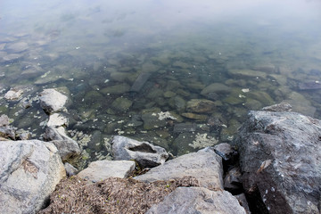 Lake shore with rocks on the bottom and on the shore.