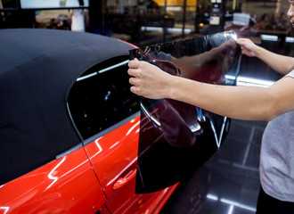 Applying tinting foil on a car window in a auto service