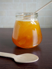 a glass jar of honey on a dark table and a wooden spoon