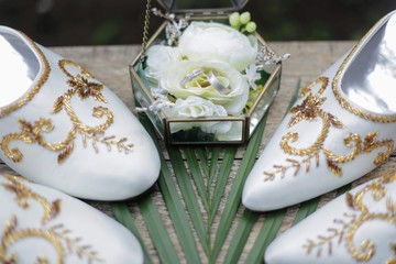 a pair of white Javanese bridal shoes with gold embroidery thread ornaments