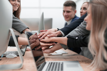 group of employees forming a stack of hands on the desktop