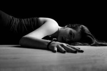 Black and white portrait of young woman lying down on a floor