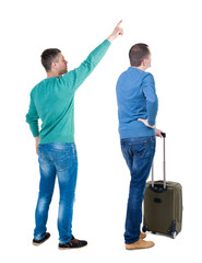 Back view of two man in sweater with suitcas.