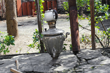Fototapeta na wymiar A teapot on a samovar in a summer courtyard stands on gray stones