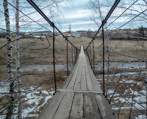 Old wooden, suspension bridge in the coniferous forest in the Ural Mountains.