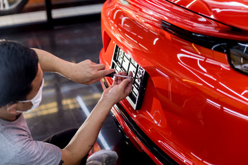Technician changing car plate number in service center.