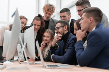 team of young employees looking together at a computer screen.