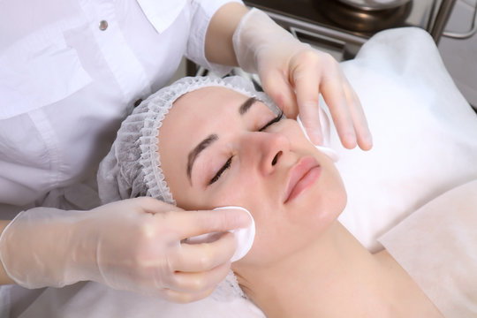 Beautician makes the cleansing procedure a young beautiful girl patient. The concept of skin care face and body