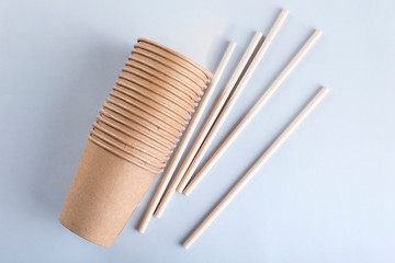 Disposable cups and drinking straws on light grey background.