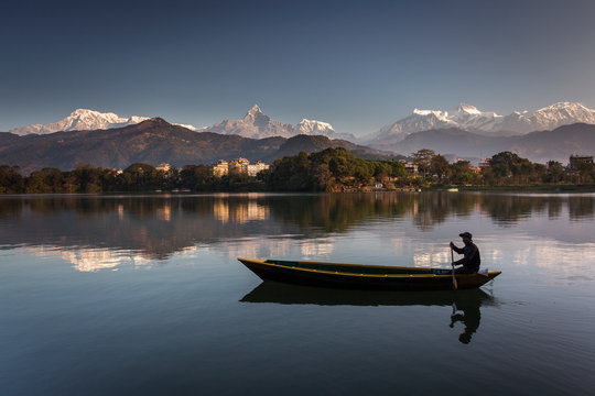 Beautiful landscape with Phewa Lake and boat on lake, mountains in background also as reflectaion on lake.  Machapuchare-FIshtail, Annapurna and many others. Pokhara, Nepal