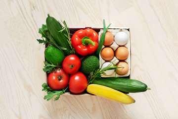 Food in a box on the floor. Fresh vegetables in a cardboard box. Fast delivery right from the store.