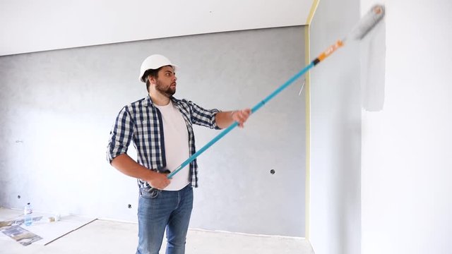 painter manually rolling the grey paint on the wall, apartment renovation