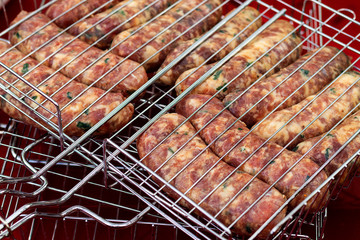 raw sausages into grill grate on the red table are ready to be grilled