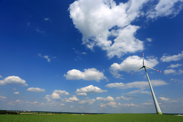 Turbina wiatrowa, wiatrak na zielonym polu, na tle niebieskiego nieba z chmurami. - obrazy, fototapety, plakaty