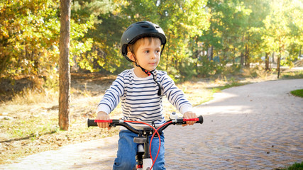 Naklejka premium Little toddler boy riding bicycle on path at park