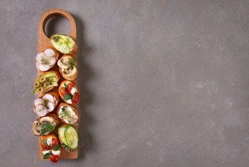 Set of bruschetta on cutting board on grey background top-down copy space